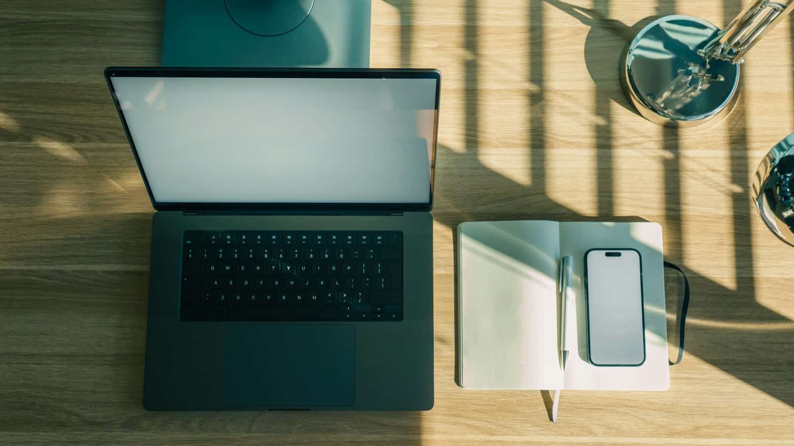 Notebook, celular e caderno organizados sobre uma mesa de trabalho