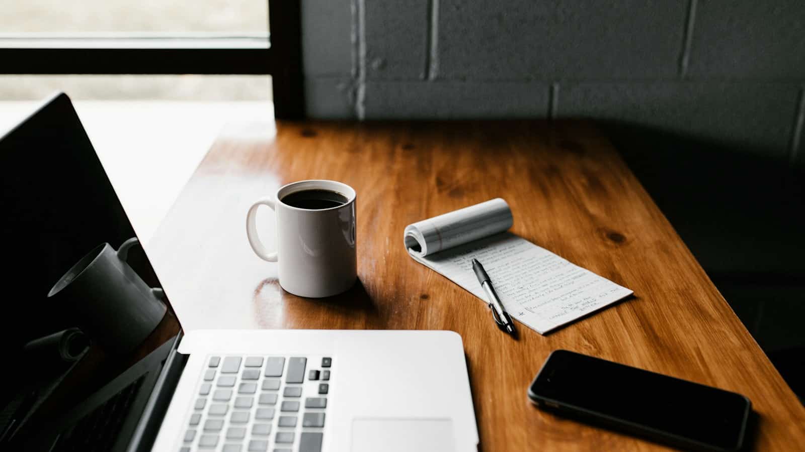Notebook, celular e caneca organizados em uma mesa