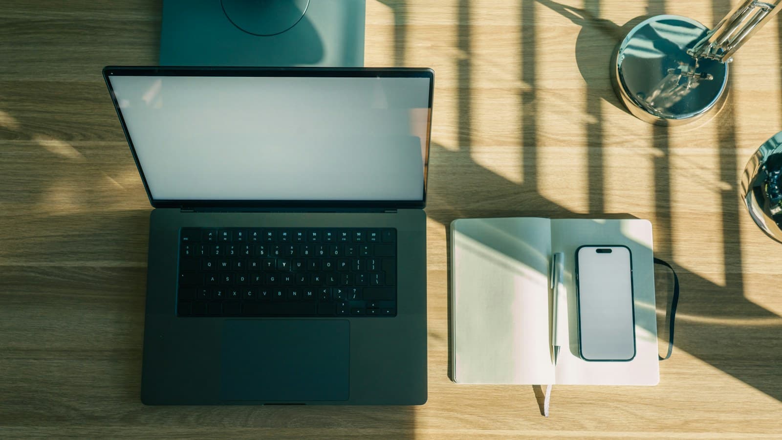 Notebook, celular e caderno organizados sobre uma mesa de trabalho