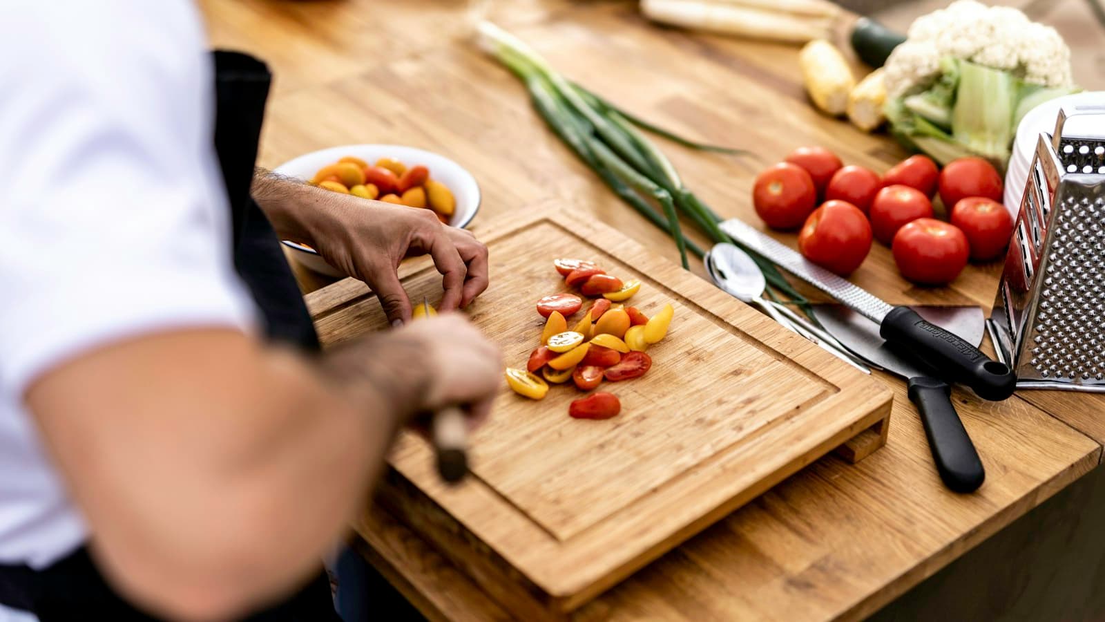 Pessoa cortando vegetais em uma tábua de cozinha